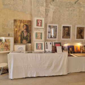 Kunstausstellung mit Gemälden und Drucken von Yvonne Brückner (Künstler Sächsische Schweiz) auf Tischen und Wänden in einem Raum mit abblätternder Wandfarbe.