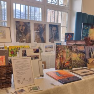 Kunstausstellung mit Gemälden und Zeichnungen auf Staffeleien und Tischen in einem Raum. Arbeiten von Künstler Yvonne Brückner